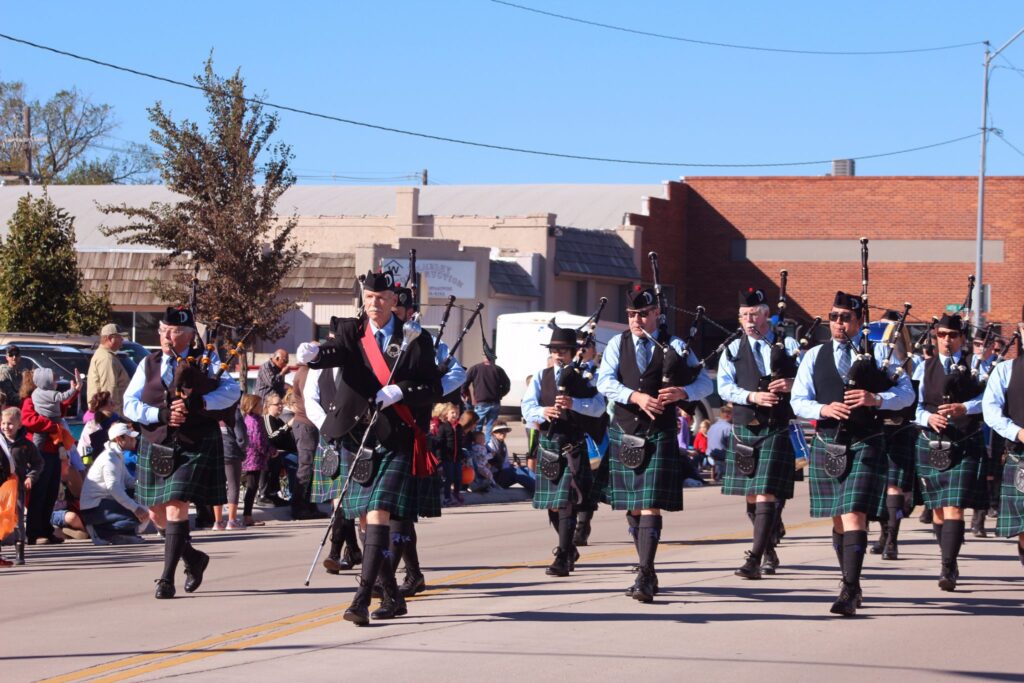 Pipe Band members marching down the street with bagpipes and kilts