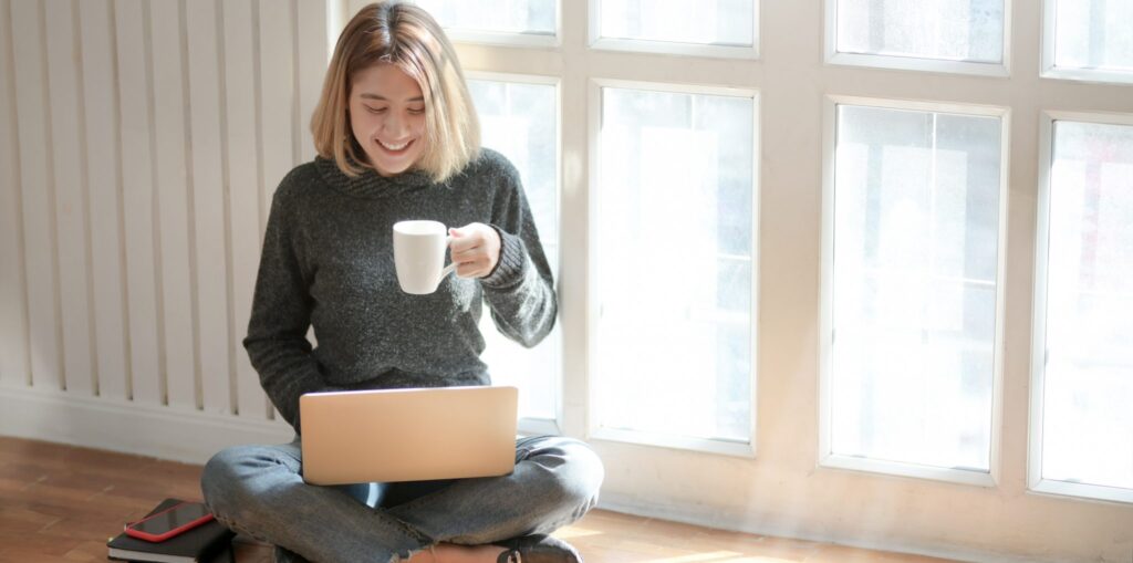 A photo of a woman with a coffee cup and laptop