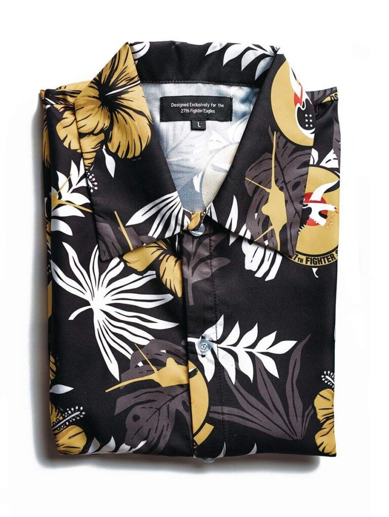 this is a black custom military hawaiian shirt, with white fronds and gold flowers, airplanes, and a squadron patch
