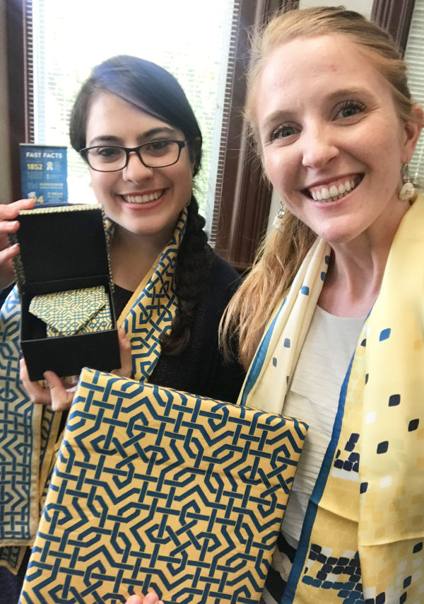 Photo of two women displaying custom print scarves, ties and scarf boxes