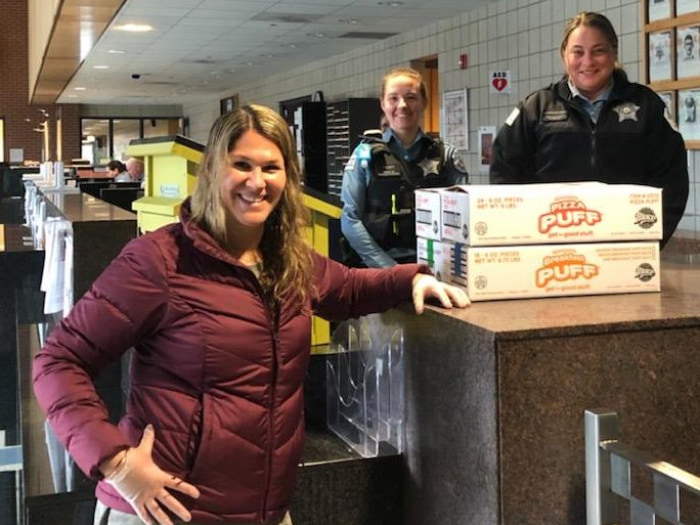 Photo of Becky and police officers with donated pizza puff boxes