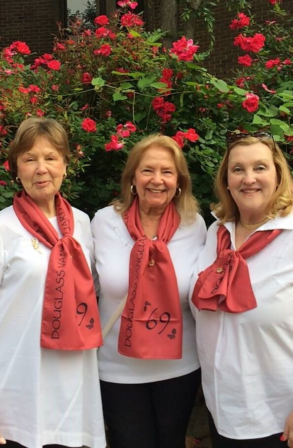 A photo of three women wearing white shirts and custom print scarves