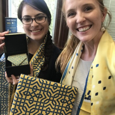 "We love them! Can’t wait to see the snakeskin ties and bow ties. We already had people stopping by our office trying to steal one of these." -- Emily Harris Photo of two women showing St. Mary's custom printed scarves, ties, and scarf boxes