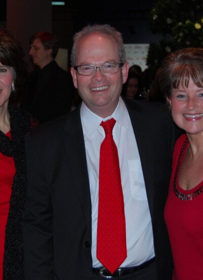 "We have two male colleagues also attending the Woman’s Day Red Dress Awards in New York on February 6th, who will be fashionably wearing their red dress ties! The ties always generate interest and conversation!" -- Marcia McCoy. <br />
Read more at the <a href="https://candorthreads.com/customer-spotlight-st-lukes-womens-heart-center/">St. Luke's Women's Heart Center</a> customer spotlight! A photo of three people attending Woman’s Day Red Dress Awards. The man inbetween the two women is wearing a custom woven tie.