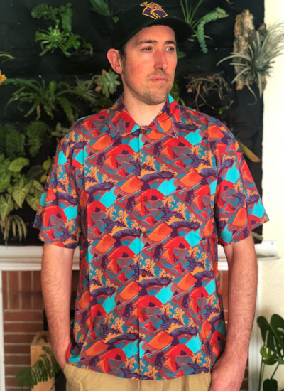 "When I had an idea for a Hawaiian shirt I wasn't so sure I could make it a reality, not with the quality I was looking for. I am so glad I chose Candor Threads to help since they were so great to work with every step of the way. When I received my shirts, I was blown away with the colors and the excellence of them! The folks at Candor Threads really know how to make an awesome Hawaiian shirt!"
- Gabriel Leonoudakis Man in colorful Hawaiian shirt with orange and blue design, standing in front of a wall full of plants